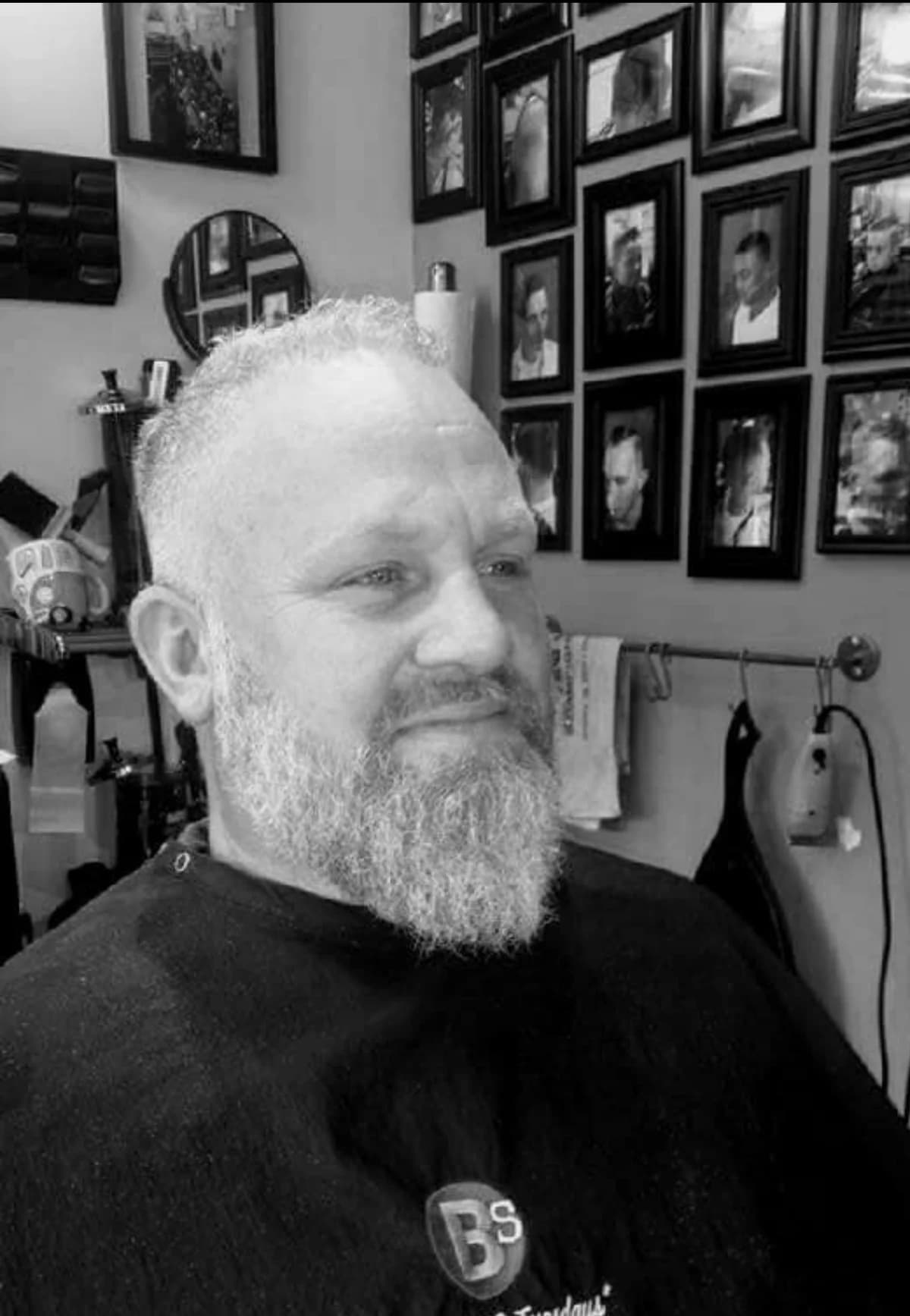 A client caped up in the chair, beard freshly shaped, in black and white.